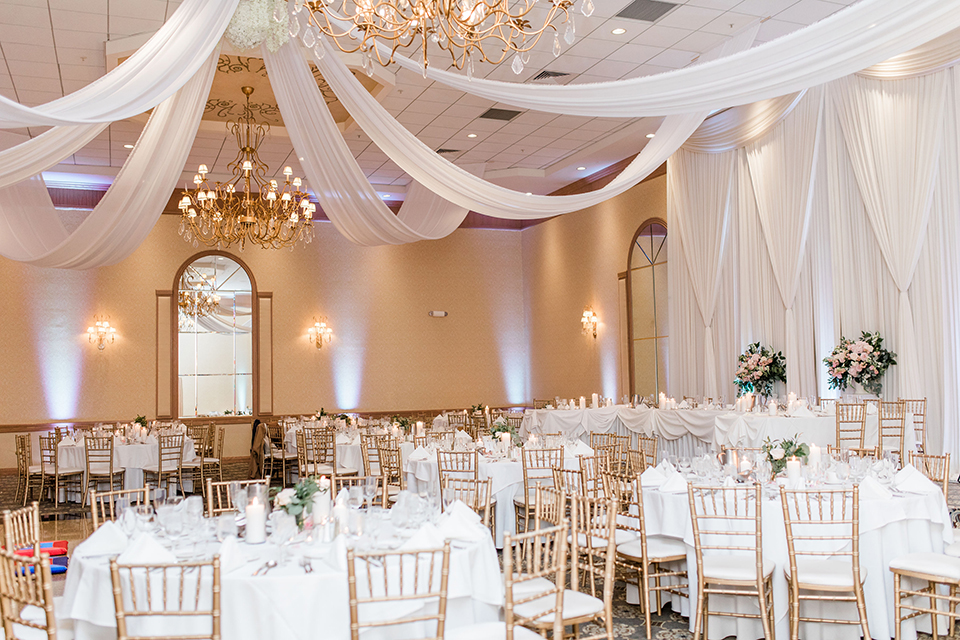  white tables with simple calligraphy table numbers with white linens draping the ceiling