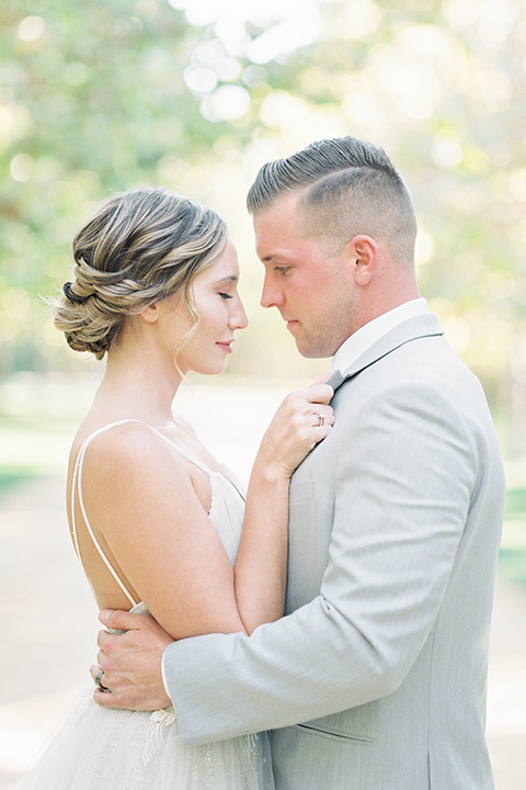 bride in a blush ballgown with thin straps and the groom in a grey suit with a white long tie