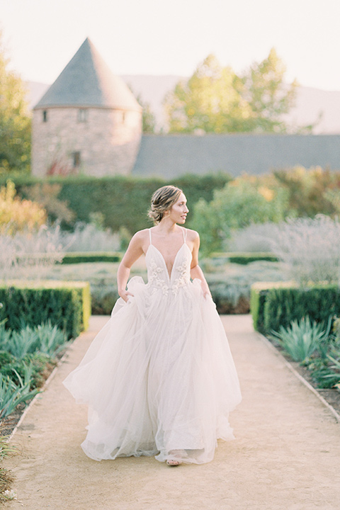  bride in a blush tulle ballgown with thin straps and hair up in a loose bun 