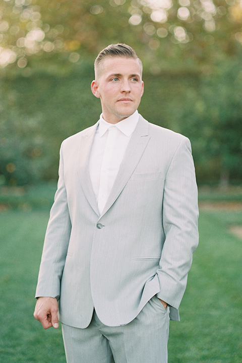 groom in a light grey suit with a white tie