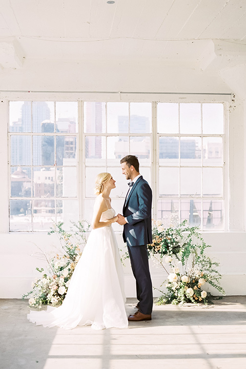  bride in a flowing modern tulle gown and the groom in a slate blue suit with grey velvet bow tie