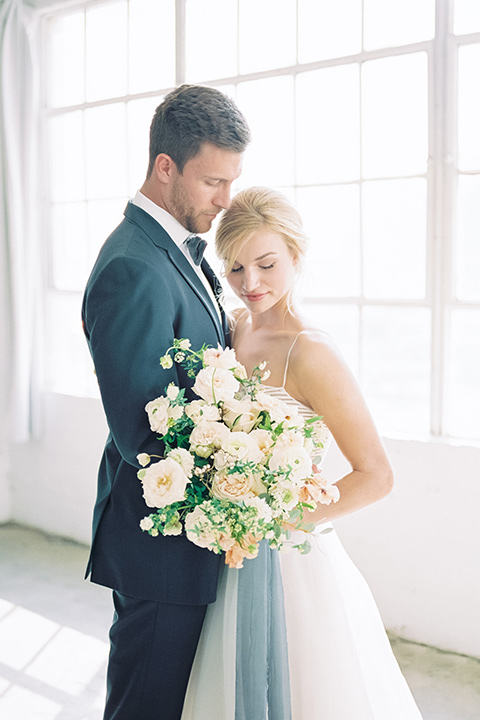  bride in a flowing modern tulle gown and the groom in a slate blue suit with grey velvet bow tie