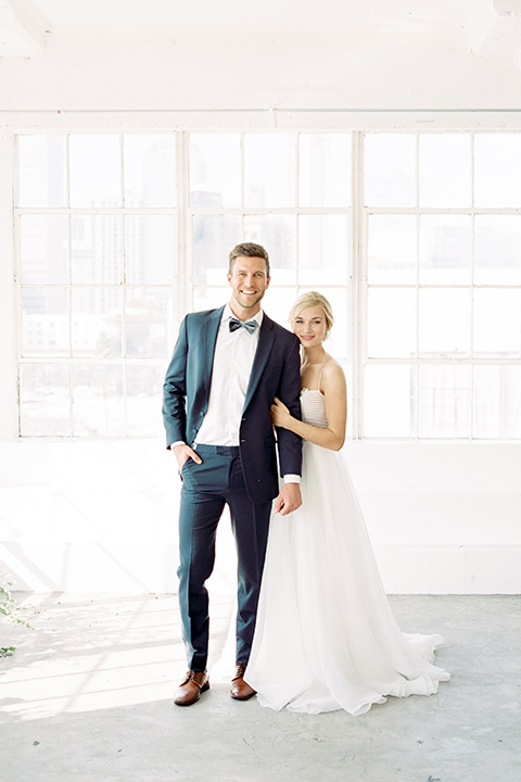  bride in a flowing modern tulle gown and the groom in a slate blue suit with grey velvet bow tie