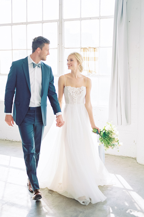  bride in a flowing modern tulle gown and the groom in a slate blue suit with grey velvet bow tie