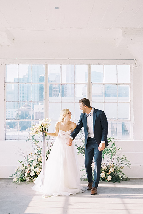  bride in a flowing modern tulle gown and the groom in a slate blue suit with grey velvet bow tie 