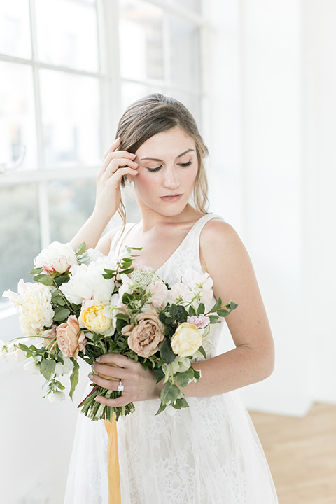  bride holding the flower bouquet in a flowing white gown with a lace detailing and straps 