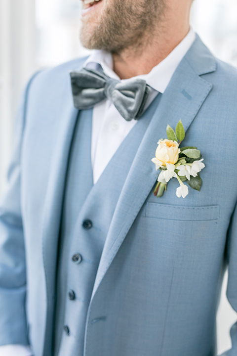  groom attire close up, the groom in a light blue suit with a grey velvet bow tie 