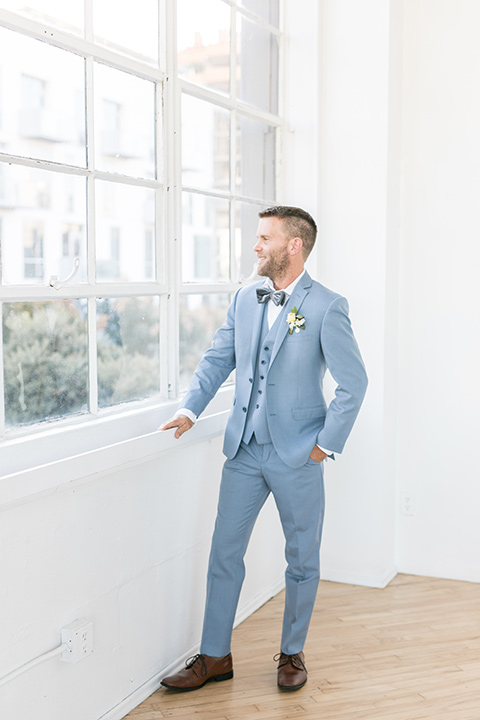 groom by the windows, the groom in a light blue suit with a grey velvet bow tie