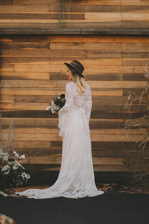 bride in a lace bohemian style gown with long flowing sleeves and a wide brimmed hat