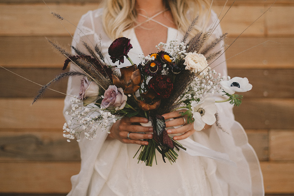  white lace gown with long billowing sleeves and bohemian white and dark flower bouquet 