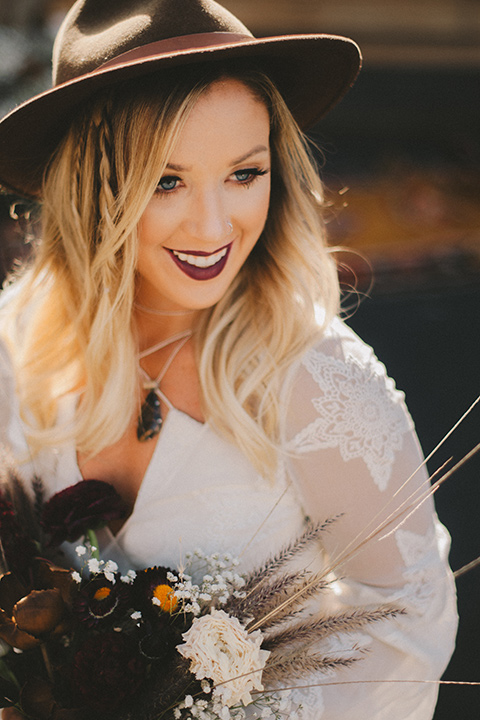  bride in a lace bohemian style gown with long sleeves and a wide brimmed hat