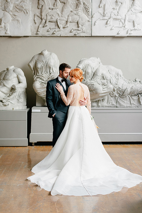  bride in a white ballgown with a crystal bodice and long sleeves with her hair in a low bun and the groom in a navy shawl lapel tuxedo with a black satin lapel