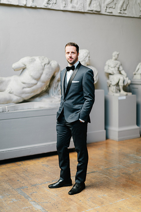  the groom in a navy blue tuxedo with black shawl lapel design and black bow tie