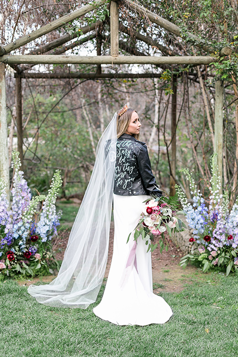 bride in a white lace gown and long sleeves and a leather jacket