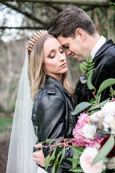  bride in a white lace gown and long sleeves and the groom in a black velvet tuxedo and a black long tie sitting together at the sweetheart table together close up