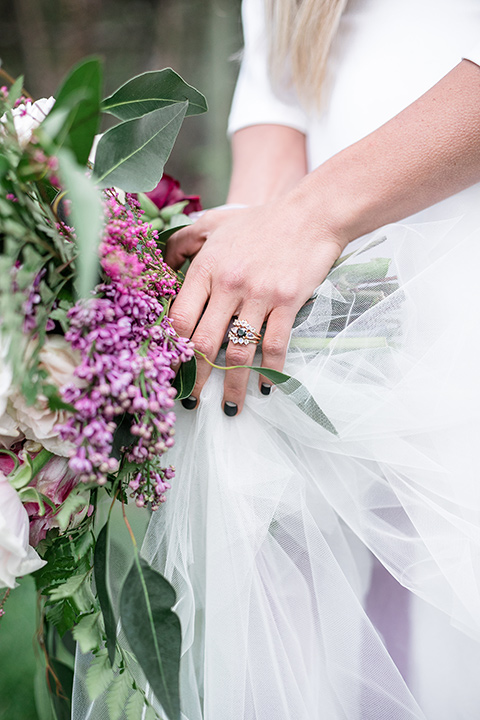  bride in a white lace gown and long sleeves and the groom in a black velvet tuxedo and a black long tie sitting together at the sweetheart table together close up