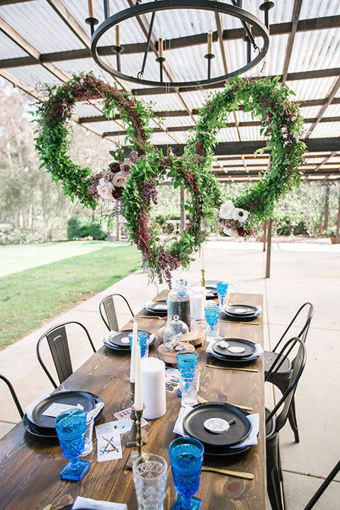 wooden table design with royal blue linens and circular floral hedges overhead