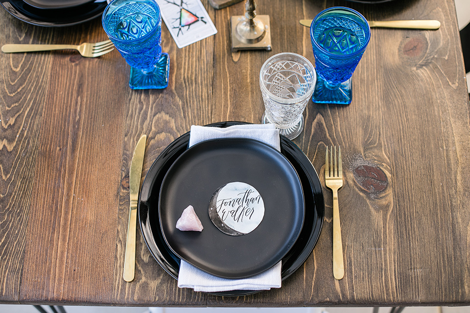  black plate design with gold flatware and royal blue drinkware 