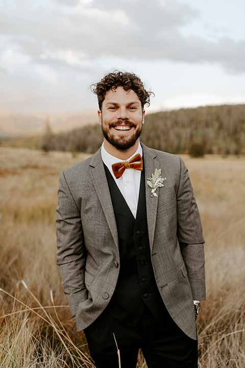  the groom in a café brown suit coat and blue pants with a gold velvet bow tie 