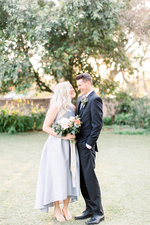  bridesmaid in a silver blue high low gown and the groomsman in a navy notch lapel suit