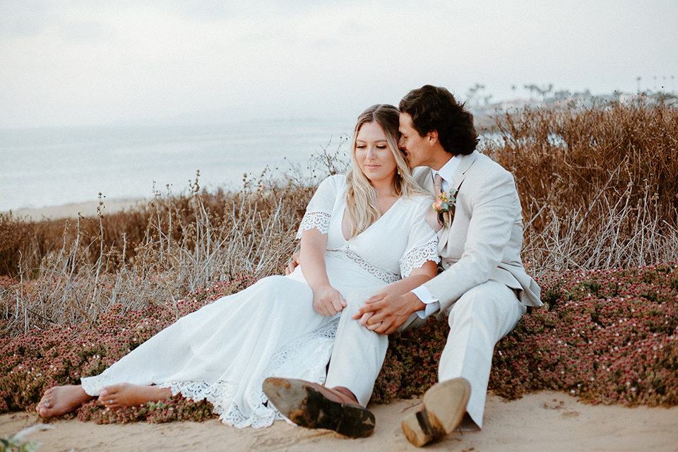  bride in a bohemian white lace gown and the groom in a light tan suit with a caramel long tie