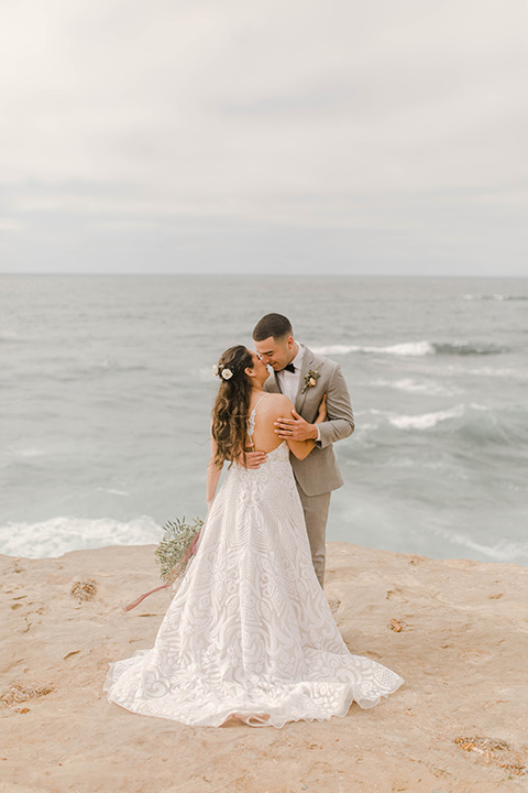 bride in a white lace gown with a soft long skirt and a low cut back and the groom in a light grey suit with the charcoal grey bow tie