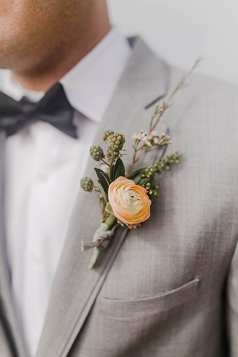  the groom in a light grey suit with a white shirt and dark grey bow tie