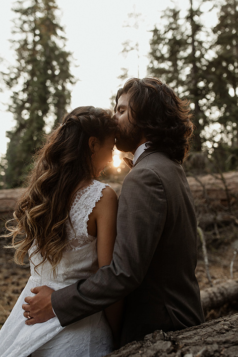  bride in a lace white gown with lace straps and a formfitting bodice and the groom in a café brown suit with a gold velvet bow tie 