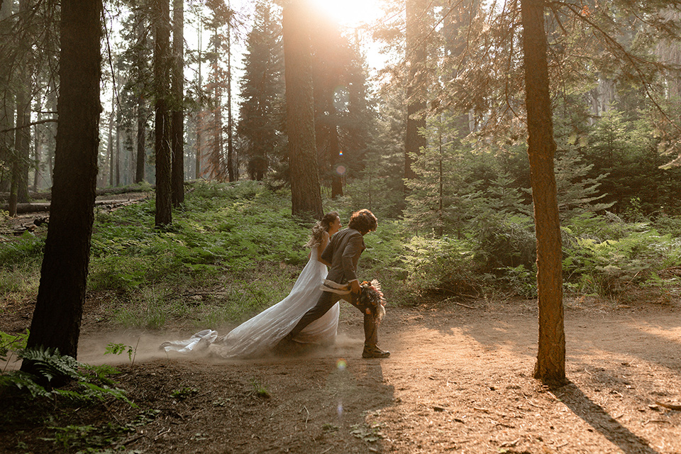  bride in a lace white gown with lace straps and a formfitting bodice and the groom in a café brown suit with a gold velvet bow tie 