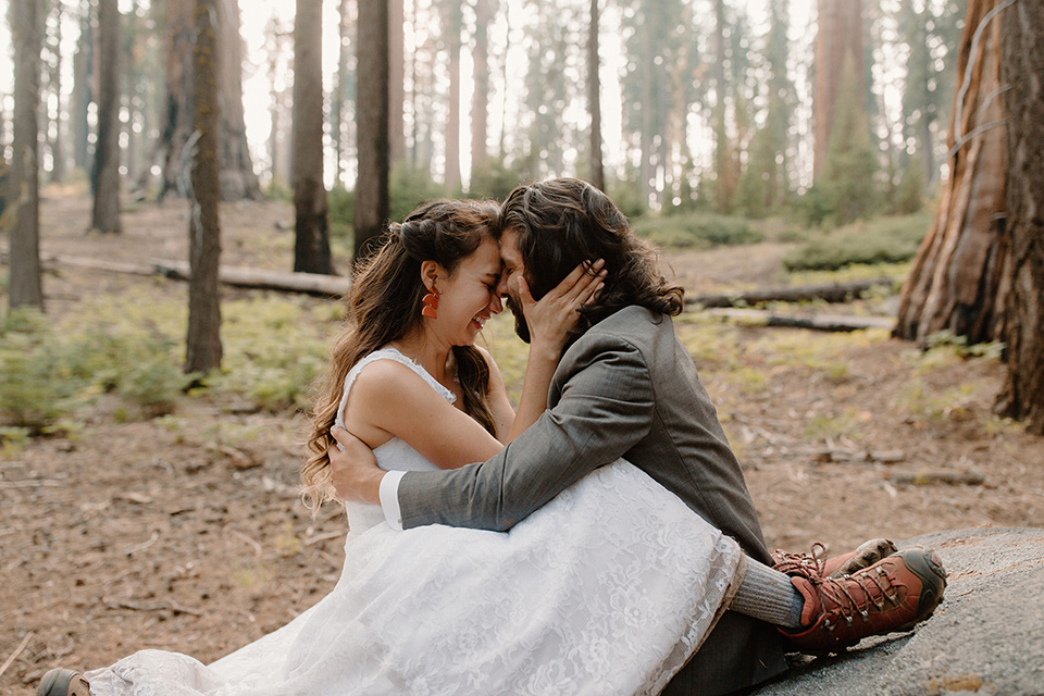  bride in a lace white gown with lace straps and a formfitting bodice and the groom in a café brown suit with a gold velvet bow tie 