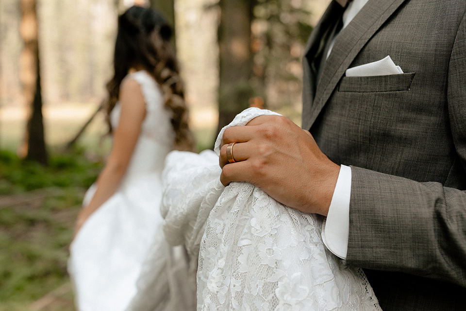  bride in a lace white gown with lace straps and a formfitting bodice and the groom in a café brown suit with a gold velvet bow tie 