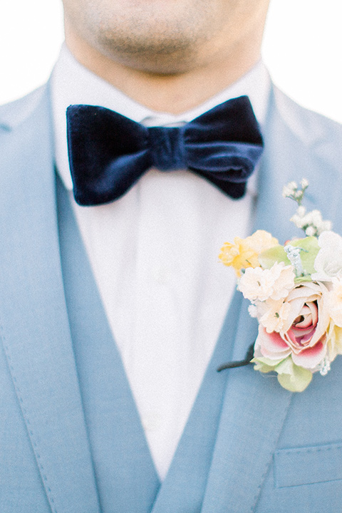  the groom in a light blue suit with a blue velvet bow tie
