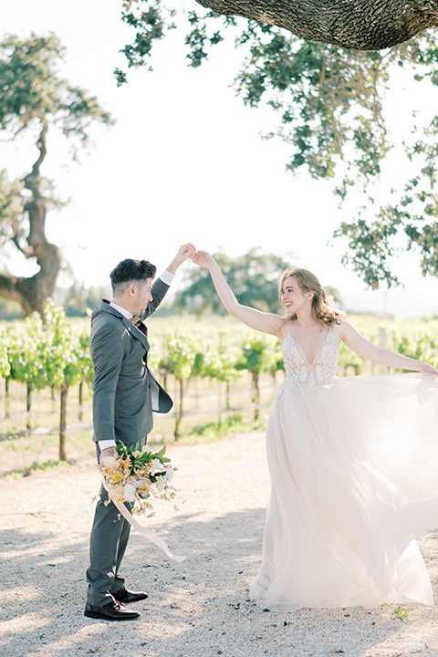  bride looking in a white flowing gown and the groom in a grey notch lapel suit with a gold velvet bow tie