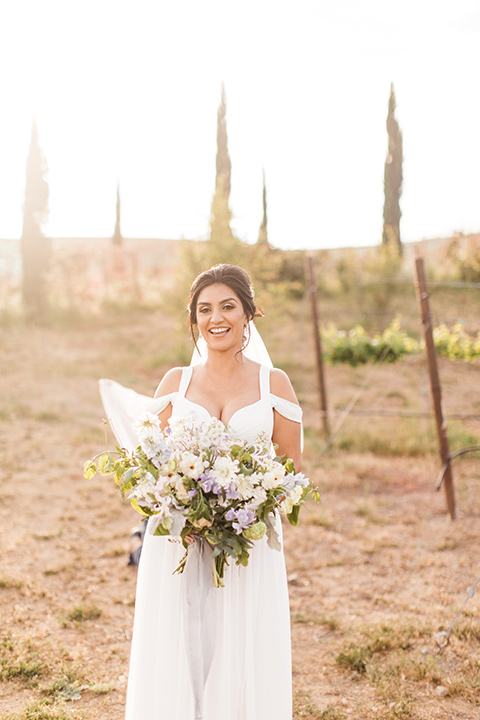  bride in a white flowing gown with off the shoulder detailing