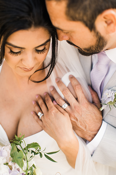  bride in a white flowing gown with off the shoulder detailing and the groom in a light grey suit with a lilac lavender long tie