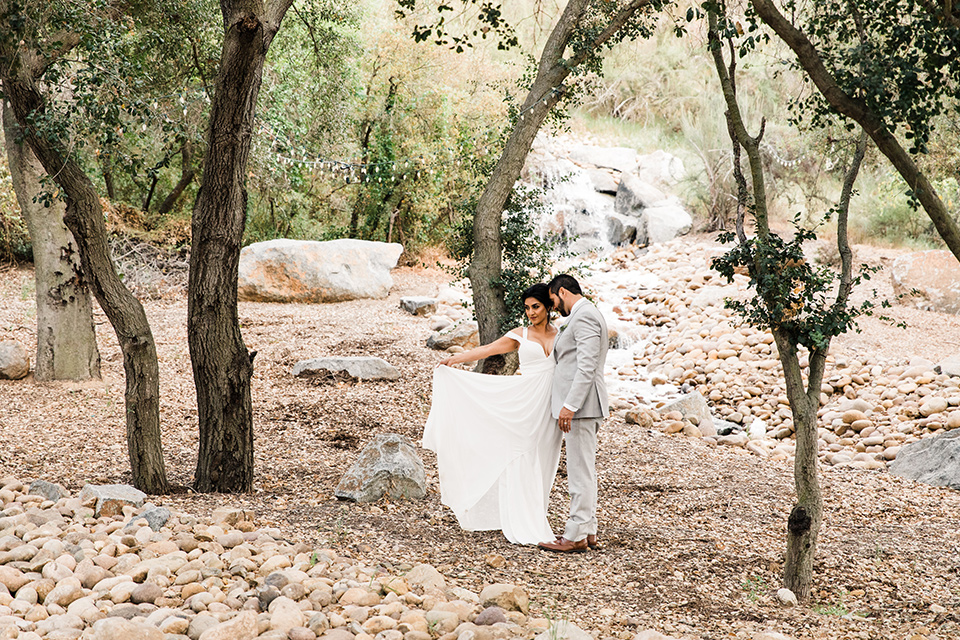  bride in a white flowing gown with off the shoulder detailing  and the groom in a light grey suit and a lavender long tie