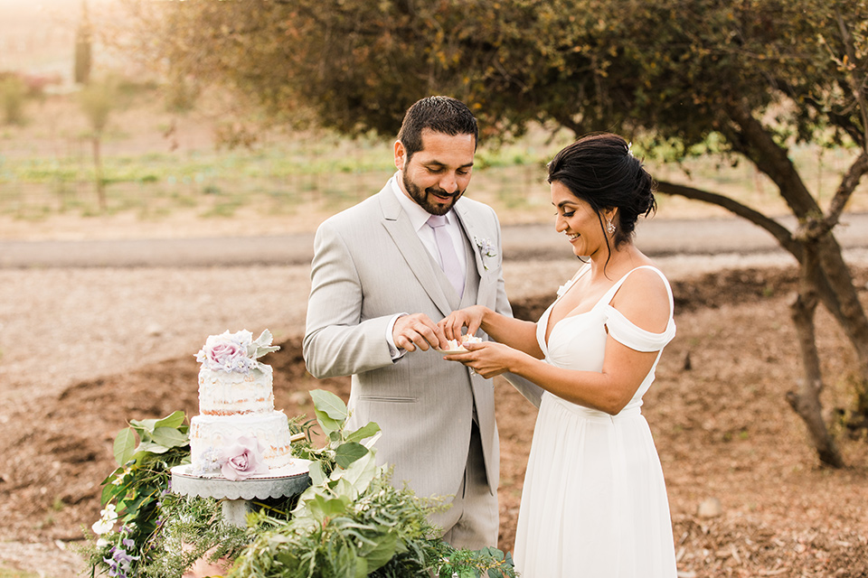  bride in a white flowing gown with off the shoulder detailing  and the groom in a light grey suit and a lavender long tie