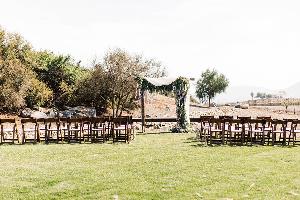  ceremony space with a wooden archway and chairs on the grass