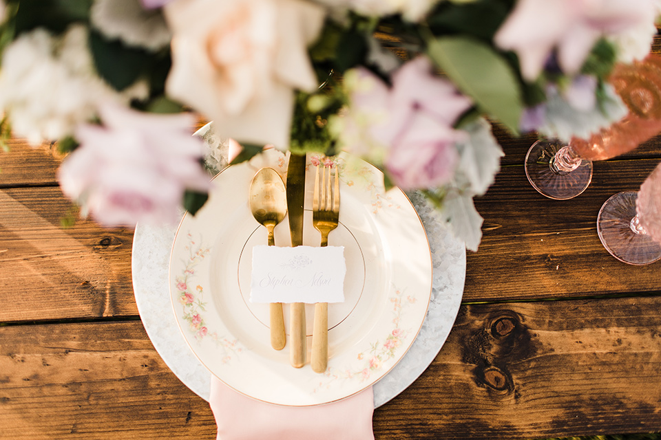  white plates with gold cutlery and lavender napkins