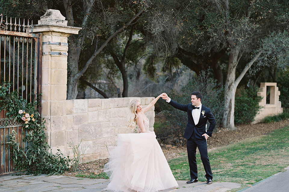  bride in a long flowing gown with long sleeves and a plunging neckline and the groom in a black tuxedo with black bow tie, dancing