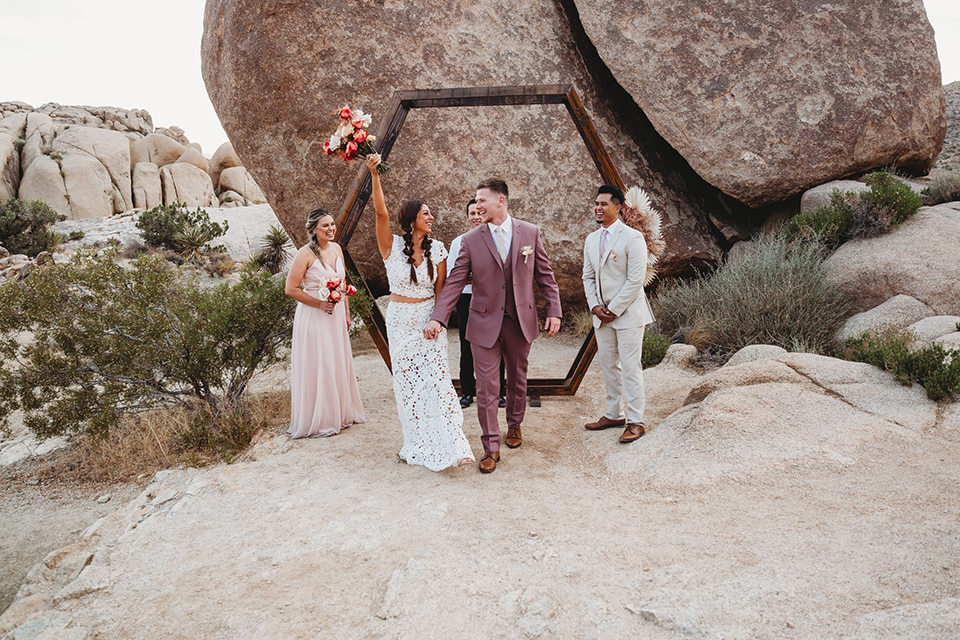  groom in a pink suit with long tie and the groomsman in a tan suit and pink tie