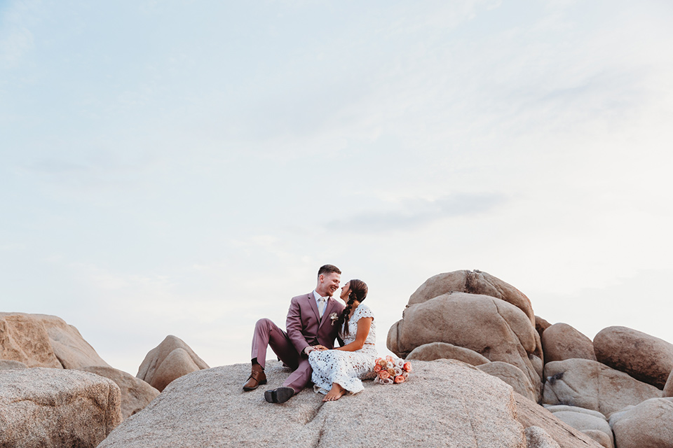  groom in a pink suit with long tie and the bride in a two piece white lace gown