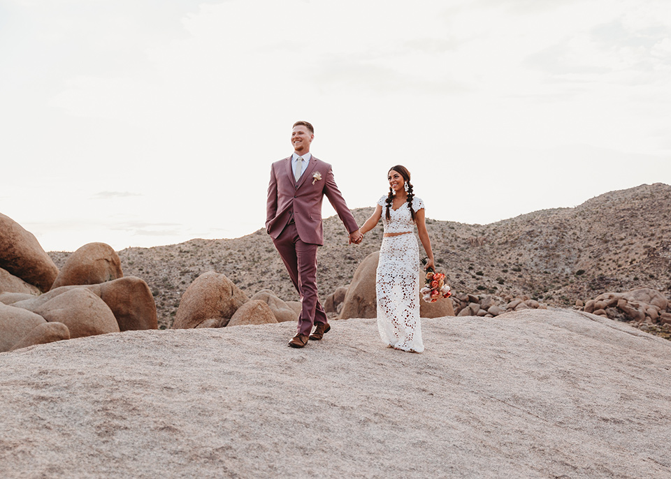  groom in a pink suit with long tie and the bride in a two piece white lace gown