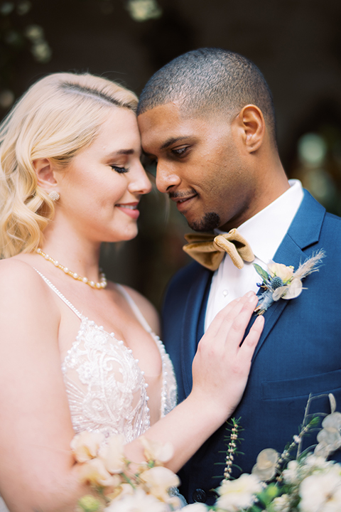 bride in a modern bohemian gown with a sheer skirt and crystal embellishments and the groom in a dark blue suit and a gold velvet bow tie