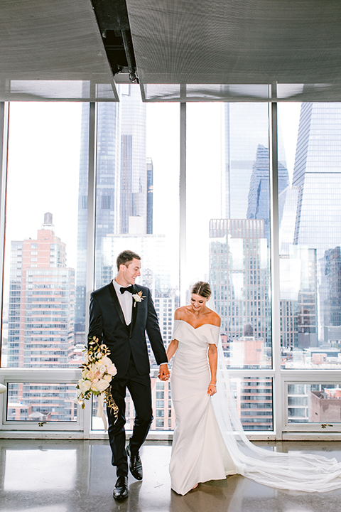   bride in a white gown with an off the shoulder detail and the groom in a blue shawl tuxedo 