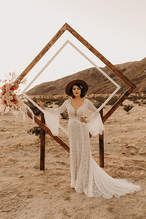  bride in a bohemian lace gown with flutter sleeves and a hat