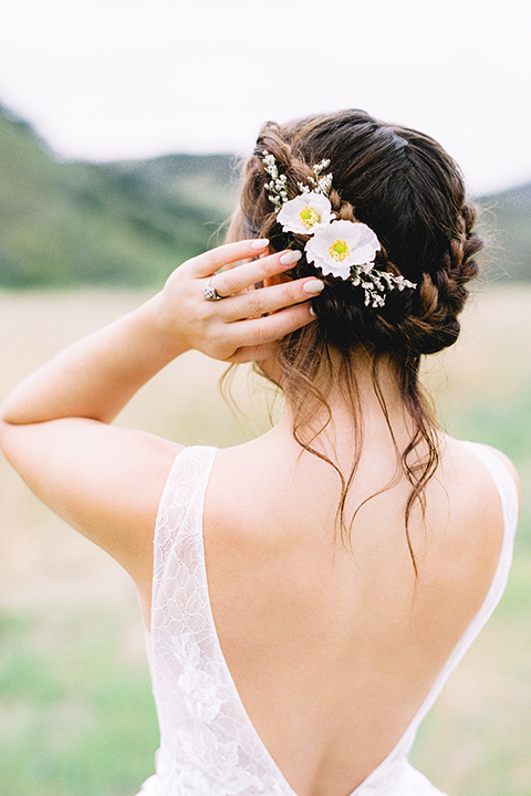  bride in a flowing bohemian gown with her hair in a loose braided bun and flowers 