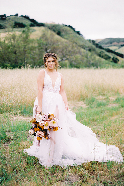  bride in a flowing bohemian gown with her hair in a loose braided bun and flowers