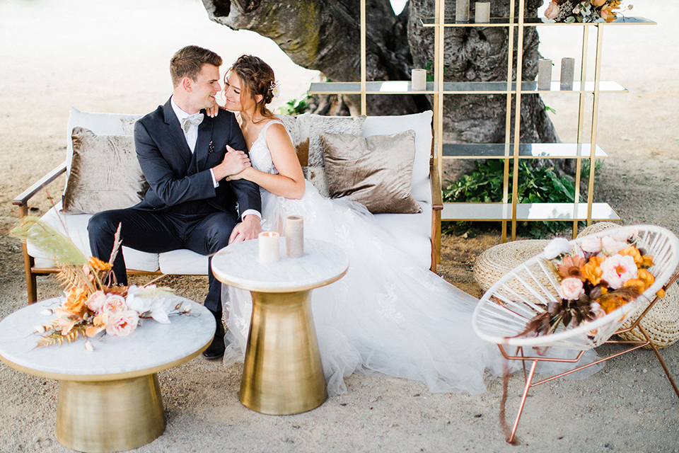  bride in a flowing bohemian gown with her hair in a loose braided bun and flowers and the groom in an asphalt grey suit 