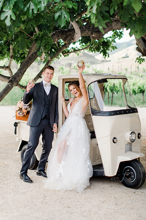  bride in a flowing bohemian gown with her hair in a loose braided bun and flowers and the groom in an asphalt grey suit